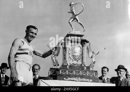 Holden gewinnt erneut den Windsor Chiswick Marathon Jack Holden mit der Marathon-Trophäe, nachdem er heute im Polytechnic Stadium, Chiswick, London, das Ziel erreicht hat. Jack Holden von Tipton Harriers, dem letztjährigen Sieger der Veranstaltung, gewann erneut den Polytechnic Harriers Kinnaird Trophy Marathon von Windsor nach Chiswick, London, als er heute (Samstag) die Distanz von mehr als 26 Meilen in 2 Stunden, 42 Minuten und 52,4 Sekunden zurücklegte. Eine Rekordzahl von 212 Wettbewerbern wurde von Prinzessin Elizabeth aus Windsor gestartet. 18. Juni 1949. (Foto von Reuterphoto). Stockfoto