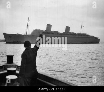 Die Queen Elizabeth in Safer Waters - Ein Blick auf den größten Liner der Welt, Queen Elizabeth, vom United Sates Public Health Service Boot Walter Wyman, als das 85.000 Tonnen schwere Cunard White Star Ship vor Quarantine vor Anker lag, als sie heute aus Schottland hierher kam. Im Vordergrund winkt ein Gruß an das mächtige Schiff, ist der erste Kumpel George Goodarce. Das große Schiff kam auf ihrer Jungfernfahrt ohne Passagiere an. 07. März 1940. (Foto von Wide World Photos). Stockfoto