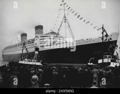 „Queen Elizabeth“ Setzt Sail On Maiden Voyage Ein -- Ein Blick vom Kai aus, während jubelende Menschenmassen dem größten Liner der Welt zusehen, wie die „Queen Elizabeth“ von Cunard-White Star, gekleidet in „Flags over all“, heute am 16. Oktober das No 2 Ocean Dock in Southampton verlässt, als sie als Luxusliner auf ihrer Jungfernfahrt nach New York in Segel setzt. 16. Oktober 1946. (Foto von Associated Press Photo). Stockfoto