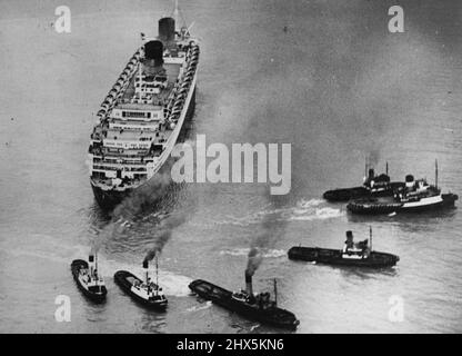 „Queen Elizabeth“ läuft auf Grund -- eine Luftaufnahme zeigt den riesigen Liner fest auf Grund, als sechs Schlepper versuchen, sie klar zu ziehen. Der Cunard-Liner 'Queen Elizabeth', der größte Liner der Welt, mit 2.446 Passagieren und einer Besatzung von 1.200 an Bord, ist während eines dichten Nebels an der Einfahrt zum Southampton Water auf Grund gelaufen. Das 85.000 Tonnen schwere Schiff kehrte von New York nach Southampton zurück. Zwölf Schlepper haben es bisher nicht geschafft, sie zu bewegen. 23. April 1947. (Foto von Sport & General Press Agency Limited). Stockfoto