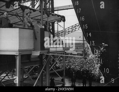 Queen startet das Southern Cross - die Flasche Empire Champagne zerbricht in einem Brunnen aus Flüssigkeit und Glas, und der neue Shaw Savill Luxusliner Southern Cross beginnt heute (Dienstag) bei ihrem Stapellauf durch die Queen vom Belfast Yard of Harland and Wolff aus den Slip zu rutschen. Der taillierte Mantel von her Majesty und der mit Federn verzierte Hut sind in Pastellgrün gehalten, der Farbe des Obermaterials des neuen Liners. Das 20.000-Tonnen-Schiff, auf dem ihr Trichter und Motoren installiert sind, pendeln zwischen Großbritannien und Australien und Neuseeland. 17. August 1954. Stockfoto