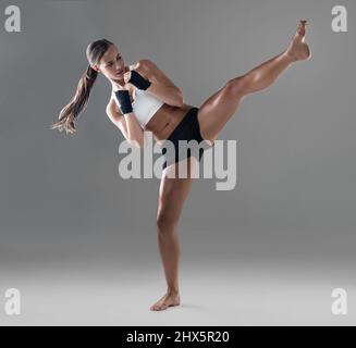 Es ist eine Stufe höher zu ziehen. Ganzkörperaufnahme einer athletischen jungen Frau, die ihre Kickboxen-Technik praktiziert. Stockfoto