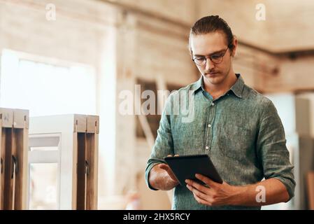 Moderne Geschäftswelt sollte moderne Technologie nutzen. Ausgeschnittene Aufnahme eines jungen Zimmermanns mit einem digitalen Tablet, während er in seiner Werkstatt arbeitete. Stockfoto