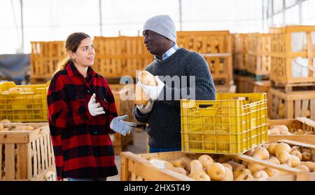 Mann und Frau Bauern reden während des Stapels von Kürbissen Stockfoto
