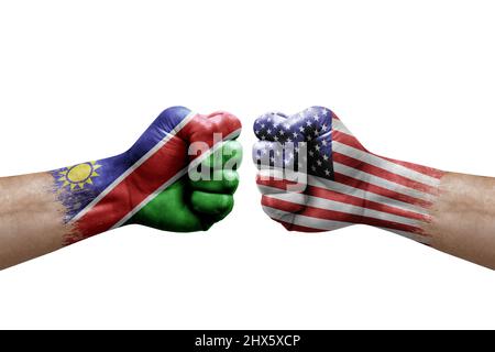 Zwei Hände schlagen sich gegenseitig auf weißem Hintergrund zu. Länderflaggen bemalten Fäuste, Konfliktkrisenkonzept zwischen namibia und den usa Stockfoto