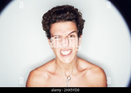Wut... übernimmt die Übernahme. Studioaufnahme eines wütenden jungen Mannes, umgeben von einem großen LichthALO. Stockfoto