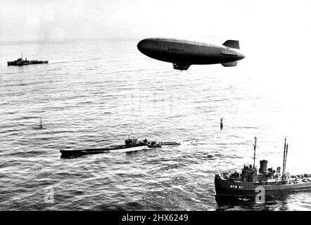 Nazi-U-Boot erreicht das Ende der Reise - ein Luftschiff der US-Marine schwebt über der U-858, dem ersten Nazi-U-Boot, das nach der Kapitulation Deutschlands die amerikanischen Streitkräfte aufgibt, da es am 14. Mai 1945 einen bestimmten Punkt der Verlegung in atlantischen Küstengewässern erreicht. Das U-Boot hatte sich ursprünglich am 10. Mai einer von zwei Zerstörer-Eskorten der Atlantischen Flotte 300 Meilen (482 km) südlich von Neufundland ergeben. Diese Eskorten, die immer noch das Nazi-Schiff flankierten, lieferten es an einen Punkt vor dem US-Ostküstenstaat New Jer Stockfoto