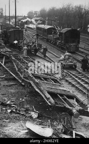 12 Dead in London Train Crash - Eine allgemeine Ansicht der Szene des Crashs, mit dem ausgebrannten Bus (Vordergrund) und dem Güterzug, mit dem er kollidierte. Mindestens 12 Menschen wurden getötet und 45 verletzt, als ein Londoner Electric-Zug durch einen Tunnel in die Rückseite eines Güterzuges rannte. Der erste der vier Wagen steht auf der stromführenden Stromleitung und bricht in Flammen auf. Viele der Opfer des Absturzes, der sich in der Nähe von Barnes ereignete, sind noch immer nicht identifiziert. 3. Dezember 1955. (Foto von Spor Stockfoto