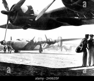 Air Corps Ferrying Command Hilft „Keep ***** Fliegende Piloten der Western Division United States Army Air Corps Ferrying Command stehen hier unter dem Flügel eines Consolidated Liberators auf dem städtischen Flughafen, von dem aus Bomber an der Westküste von diesen Piloten zu unbekannten Zielen in den Norden und Osten geflogen werden, Dort werden die Flugzeuge an Piloten der Royal Air Force überführt, die sie in die Kampfzonen fliegen. Ferry Command Piloten sind junge Männer, von denen viele keine mehr haben Stockfoto