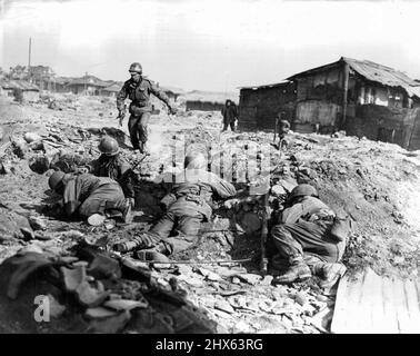 Ein Infanterist der US-Armee rennt mit anderen Mitgliedern seiner Einheit zur Schutzhülle, während sie sich vor dem kommunistischen Kleinwaffenfeuer in der Republik Korea schützen. Das Foto zeigt, wie koreanische Städte und Dörfer aufgrund der nordkoreanischen und chinesischen kommunistischen Entschlossenheit, aus besiedelten Gebieten Schlachtfelder zu machen, verwüstet wurden. 24.Mai 1951. Stockfoto