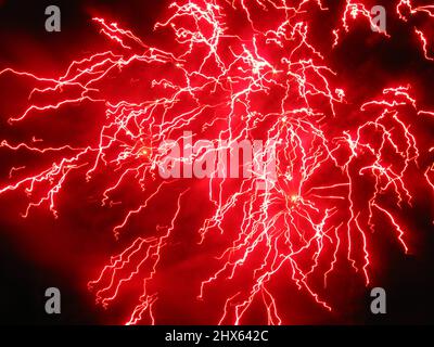 Farblich psychedelisches Feuerwerk ruft wie eine Gabel in einer Steckdose elektrische Stöße und Spannungen hervor. Stockfoto