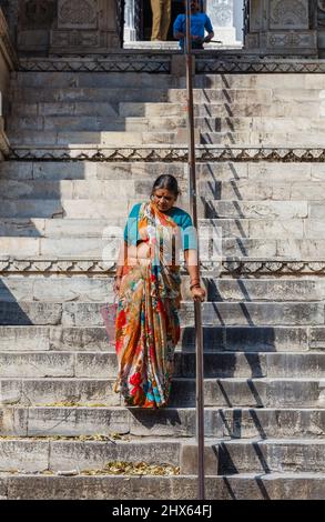 Eine ältere Frau in einheimischer Kleidung steigt mit einem Handlauf am Eingang zum Hindu Shree Jagat Sheromani Ji Tempel, Udaipur, Rajasthan, Indien, die Stufen hinab Stockfoto