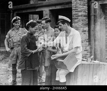 Eines der ersten chinesischen Mädchen, das wieder für die britischen Streitkräfte arbeitet, die unter dem Konteradmiral CHJ Harcourt, CB, CBE, den Hafen von Hongkong besetzten, wird von A. Blues in Reis bezahlt. R.M.T. Salisbury und P/O P. Laves sehen aus. 24. September 1945. (Foto von einem offiziellen Foto der Royal Naval) Stockfoto