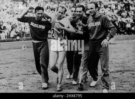 Die XIV. Olympiade - Tscheche gewinnt die 10.000 Meter -- E. Zatopek (Tschechoslowakei), nachdem er die 10.000 Meter im Wembley-Stadion gewonnen hatte, wobei er von Mitgliedern des jugoslawischen Teams von der Strecke unterstützt wurde. 8. Oktober 1948. (Foto: Sport & General Press Agency, Limited). Stockfoto