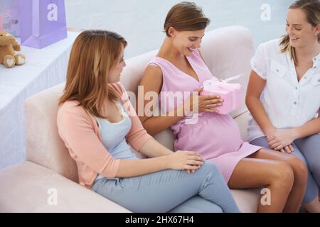 Was ist in der Box. Eine junge Schwangerin erhält Geschenke für ihr kleines Mädchen an der Babydusche. Stockfoto