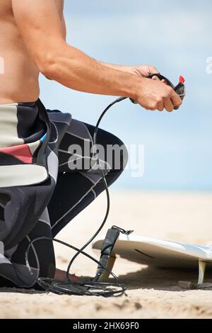 Machen Sie sich bereit zum Surfen. Ein junger Mann in einem Neoprenanzug, der sich zum Surfen vorbereitet. Stockfoto