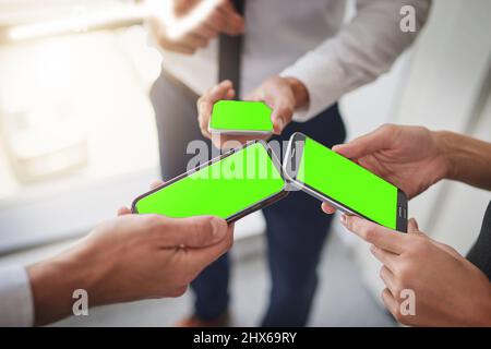 Dinge im smarten Zeitalter geschehen lassen. Ausgeschnittene Aufnahme einer Gruppe von Kollegen, die ihre Smartphones synchron nutzen. Stockfoto