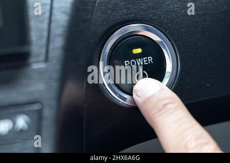 Drücken Sie mit dem Finger auf einen Netzschalter, um den Motor anzulassen Stockfoto