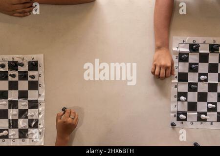 Draufsicht auf eine Gruppe von Kindern in einer Schule, die einen Moment der Erholung beim Schachspielen haben Stockfoto