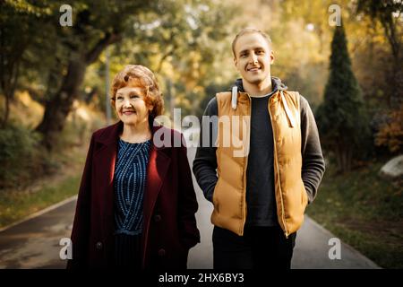 Glückliche Mutter mit erwachsenem Sohn stehen mitten im Park unter den Bäumen im Freien. Hochwertige Fotos Stockfoto