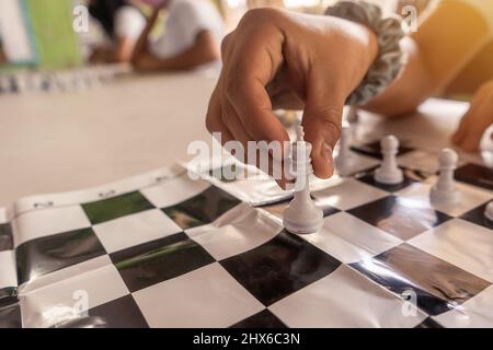 Nahaufnahme der Hand eines Schulmädchen, die das Queen-Stück eines Schachbretts bewegt Stockfoto