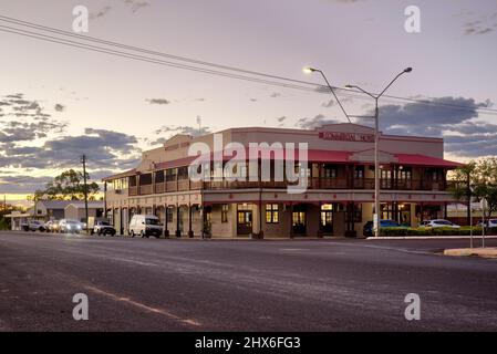 Blick in die Dämmerung auf ein altes Kolonialgebäude in einer ruhigen Straße mit klarem Himmel und Straßenbeleuchtung. Commercial Hotel (1938) Clermont Queensland Stockfoto