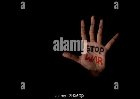 Unverkennbare Hand mit Stop war geschrieben, zeigt mit Kopierraum in dunklem Hintergrund - Konzept von Unabhängigkeit und Freiheit Stockfoto