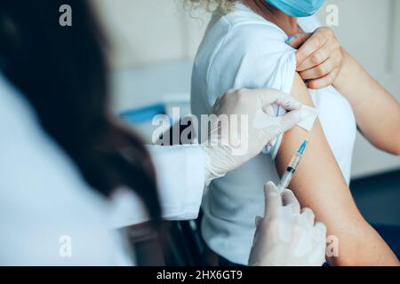 Die Hände einer Ärztin, die einen Schuss in die Schulter eines Patienten machte, Impfungen während einer Pandemie-Situation. Nahaufnahme für Lifestyle-Design. Coronavirus Stockfoto