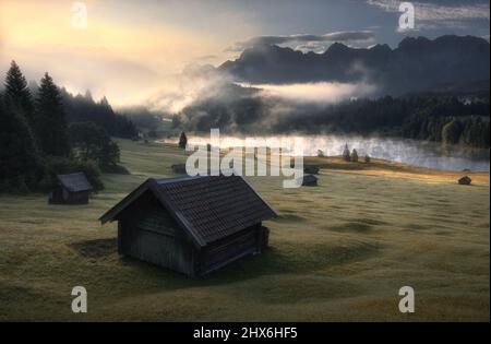 Hütte auf einer Wiese im Hintergrund See und Berge Stockfoto
