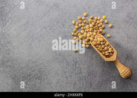 Ungekochte braune Linsen. Rohe Hülsenfrüchte in Holzlöffel. Draufsicht. Stockfoto
