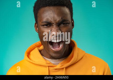 Emotional schreiender junger afrikanischer Mann, der isoliert über dem Hintergrund der Minze steht Stockfoto