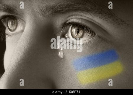 Mann mit ukrainischer Flagge, der weint. Russland und Ukraine Krieg. Rettet die Ukraine und beendet den Krieg Stockfoto