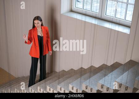 Geschäftsfrau in roter Jacke steht mit durchdachtem Blick auf Treppen, denkt über einen Businessplan für die Zukunft nach, sorgt sich um die zukünftige Finanzkrise Stockfoto