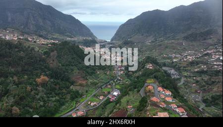 Kleines städtisches Dorf zwischen hohen Klippen in einer tropischen grünen Landschaft, Aussichtspunkt mit Luftdrohnen. Stockfoto