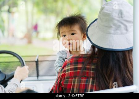 Baby mit Frau, die im Golfwagen sitzt, um im Zoo zu reisen Stockfoto