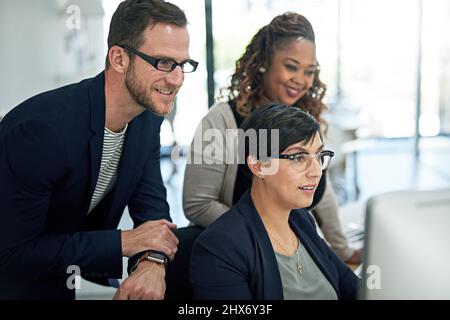Sehen Sie sich das an. Eine kurze Aufnahme von drei Kollegen, die im Büro arbeiten. Stockfoto