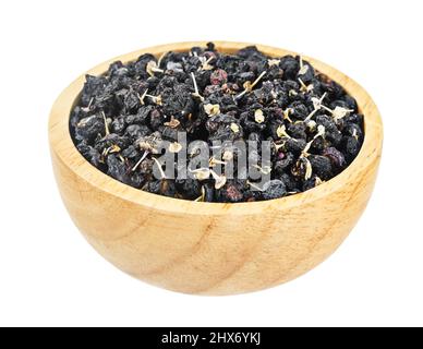 Getrocknete schwarze Wolfbeeren oder schwarze Goji-Beeren in Holzschüssel isoliert auf weißem Hintergrund, Speichern Clipping Pfad. Stockfoto