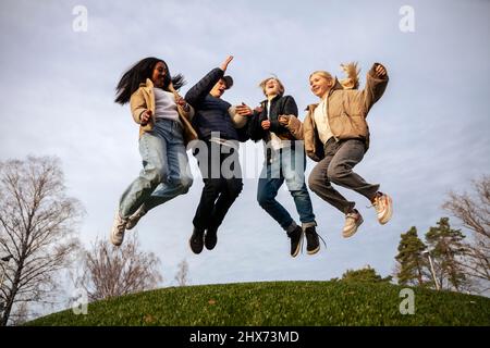 Blick aus der unteren Perspektive auf die springenden Freunde im Teenageralter Stockfoto