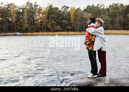 Paar stehen am See und umarmen Stockfoto