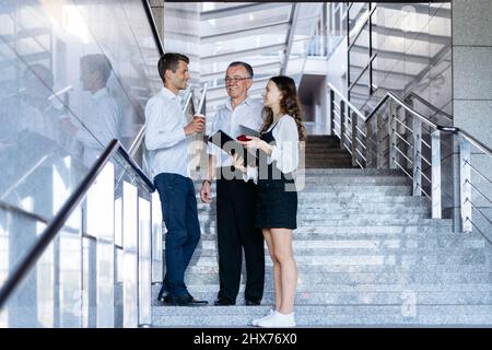 Das Business-Team mit Kaffee zum Mitnehmen steht auf der Treppe im Business-Center. Stockfoto