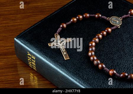 Bibel und Rosenkranz auf einer polierten Tischplatte Stockfoto