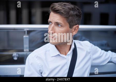 Seriöser junger Geschäftsmann, der auf einer Bank sitzt. Nahaufnahme. Stockfoto