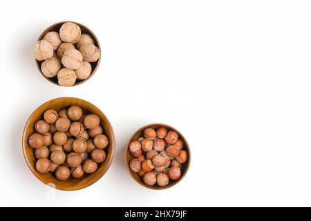 Natürliche Bio-Macadamia, Walnuss, Haselnüsse in Holzschale auf weißem Hintergrund Flat Lay Draufsicht gesunde Snack Nüsse mit ätherischem Öl reich an vi Stockfoto