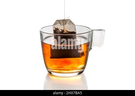 Infundierter Teebeutel erzeugt Tee in heißem Wasser in der durchsichtigen Glasschale, die auf weißem, schneidenden Pfad isoliert ist Stockfoto