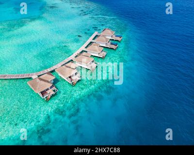 Überwasser-Villen auf tropischer Atoll-Insel für Urlaubsreisen und Flitterwochen. Luxus-Resort-Hotel auf den Malediven oder der Karibik mit türkisfarbenem Meer Stockfoto