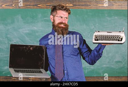 Wählen Sie die richtige Lehrmethode. Digital gegen Retro. Moderne Technologien profitieren. Modern statt veraltet. Lehrer bärtiger Hipster hält Schreibmaschine Stockfoto