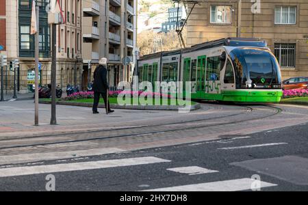 BILBAO, SPANIEN-DECEMBER 19, 2021 : Ältere Menschen, die in der Nähe der Stadt Euskotren gehen, fahren mit der Straßenbahn. Moderner Verkehr in Europa. Gehweg in smart Stockfoto