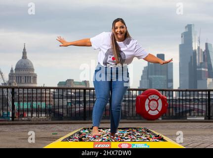 REDAKTIONELLE VERWENDUNG NUR die Schauspielerin Jacqueline Jossa geht barfuß über einen Backsteinpfad aus 30.000 LEGO Steinen am Observation Point in London, um Geld für den Red Nose Day 2022 von Comic Relief zu sammeln. Bilddatum: Donnerstag, 10. März 2022. Stockfoto