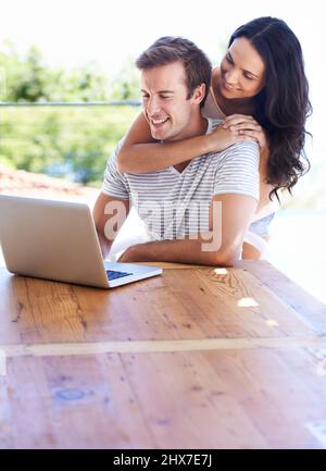 Draußen im Internet surfen. Ein junges Paar, das seinen Laptop auf der Terrasse benutzt. Stockfoto
