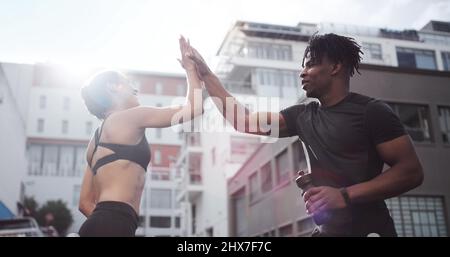 Ich glaube an dich. Aufnahme eines jungen Paares, das sich gegenseitig einen High-Five gab, während es draußen in Sportkleidung stand. Stockfoto